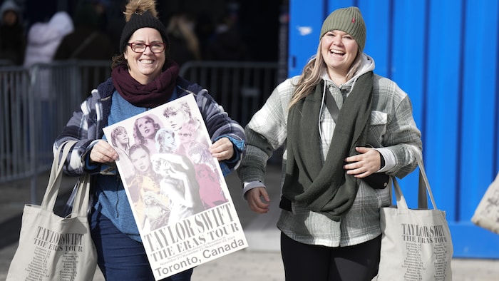 Des admiratrices de Taylor Swift sortent du Centre Rogers de Toronto avec une affiche de la vedette, le 13 novembre 2024.